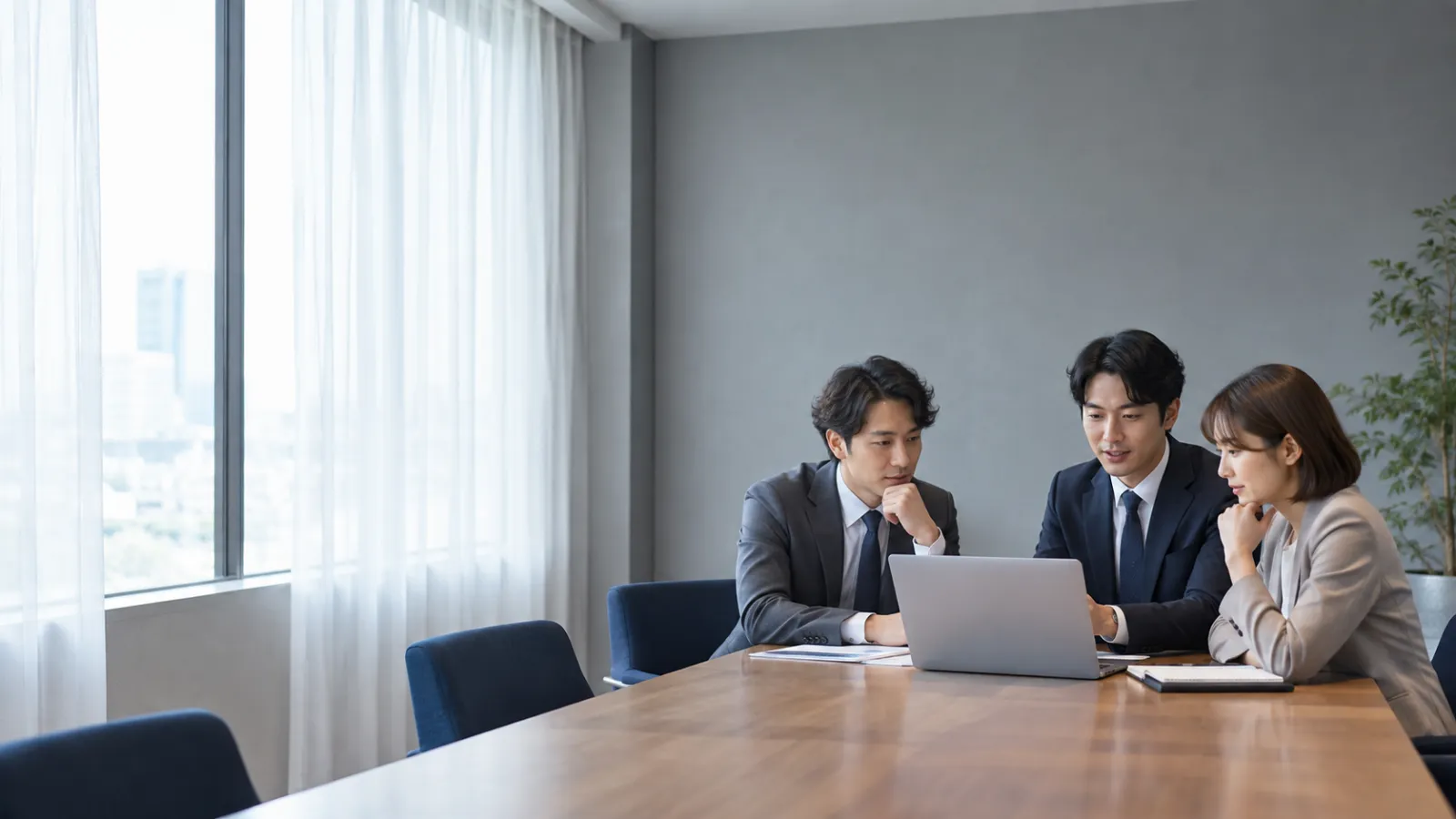 会議室でノートパソコンを囲んで打ち合わせをするチーム